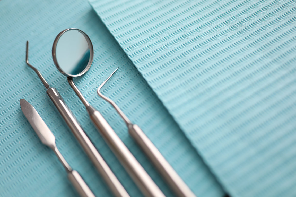 Pile of dentist tools lying at green tissue ready to be used close-up