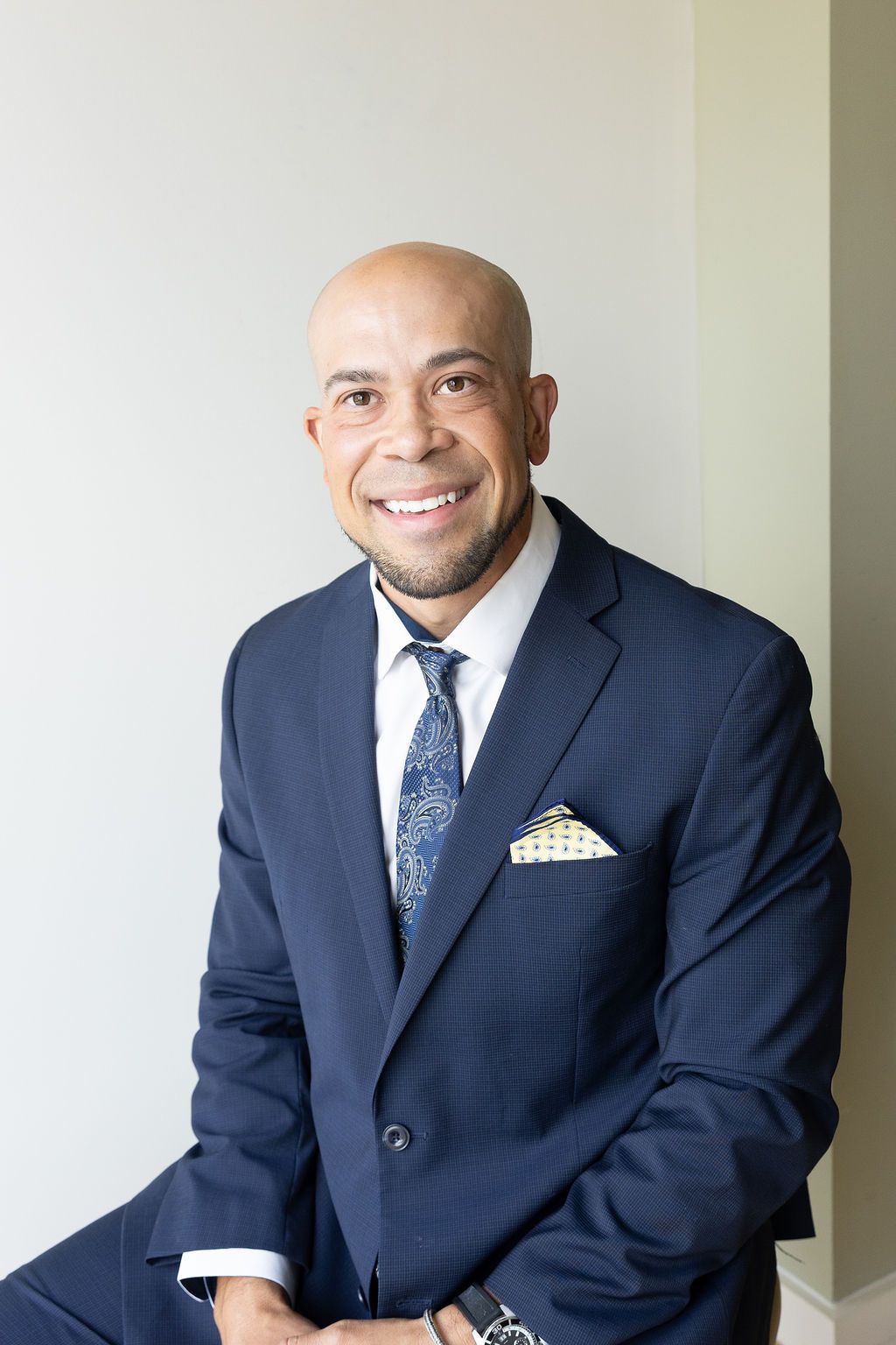 Dentist in navy suit seated, color professional portrait