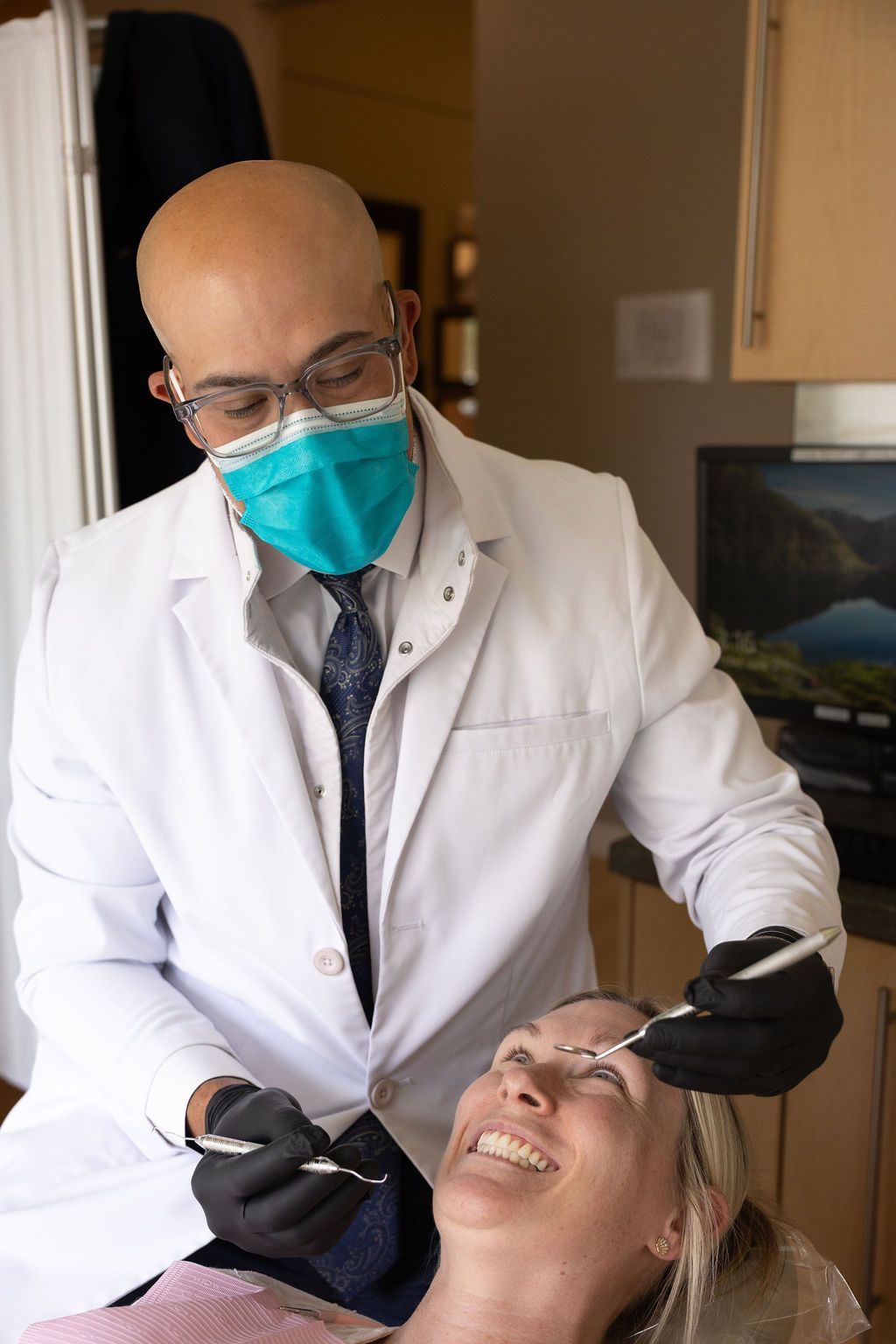 Sunrise Dental Cary dentist in white coat examining patient's teeth with dental tools