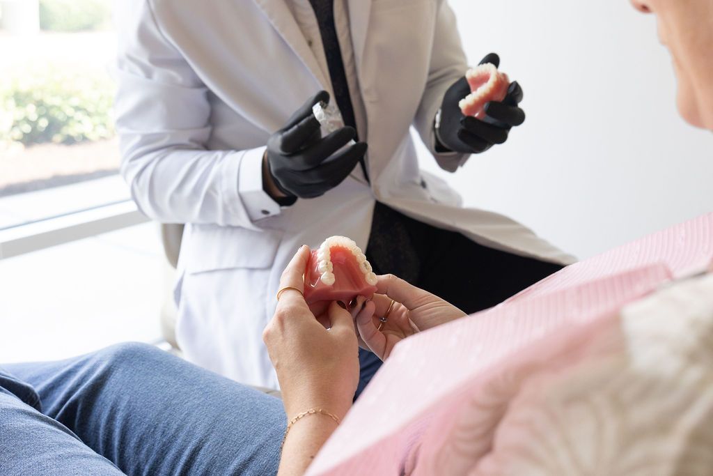 Dentist presenting red denture model to patient during consultation