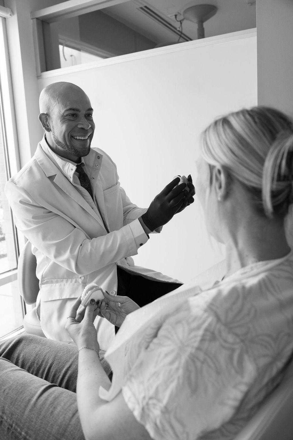 Dentist consulting with patient, showing dental model in office