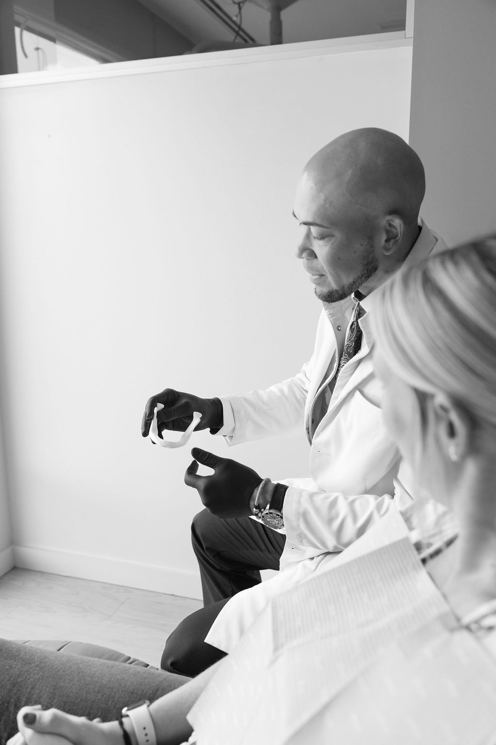 Dentist consulting with patient in office, holding dental model